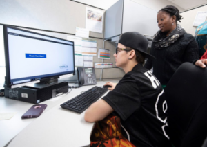 Image of YSM employment services client on a computer alongside a YSM staff member